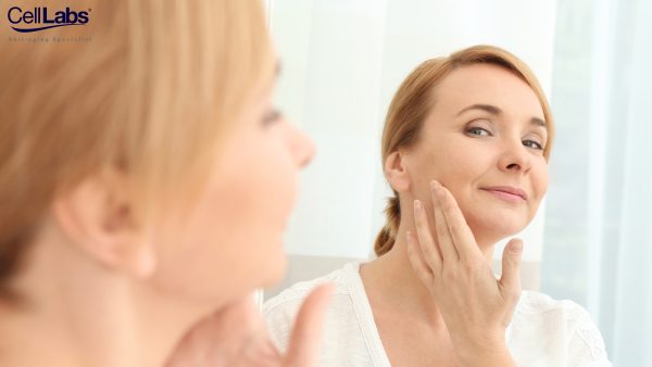 Image of a middle-aged woman looking at her face in a mirror.